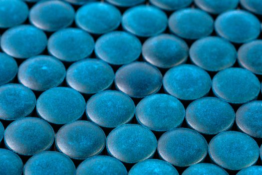 close-up background of many blue organic spirulina tablets laid tight in one layer on flat surface.