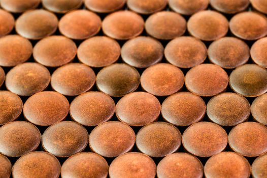 close-up background of many orange organic powder tablets laid tight in one layer on flat surface.