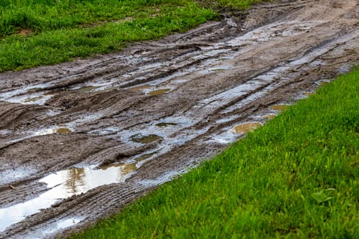 dirty clay mud road with puddles and tire tracks - closeup with selective focus and blur, diagonal composition