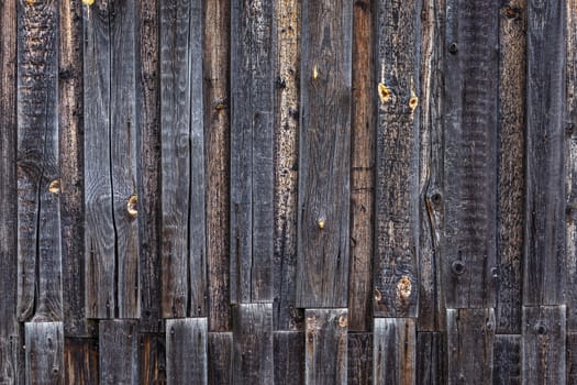 artistic texture of an old wooden planks fence in black and brown tones - close-up rustic background