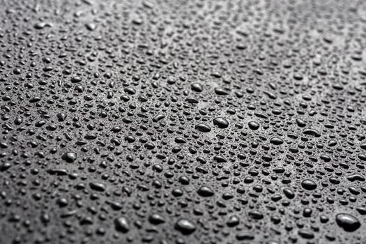 water drops on abstract flat black hydrophobic surface macro background with selective focus and blur