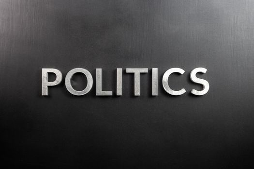 the word politics laid with aluminium letters over matte black flat surface - directly above perspective in center of picture