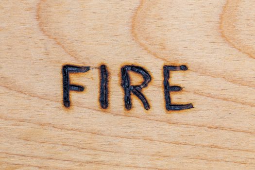 the word fire handwritten on flat wooden surface with electrical woodburner