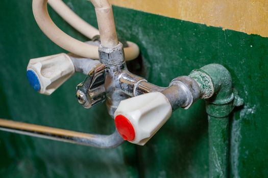 a close-up view of stained old russian chrome water faucet, focus on foreground, blur on background