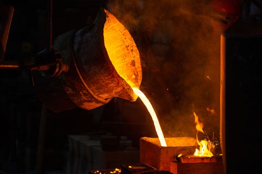 Close-up view of industrial chill casting with selective focus. The process of for filling out mold with molten metal.