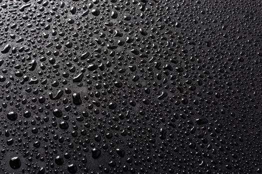 close-up view of water drops on black flat matte surface macro sith selective cous and background blur