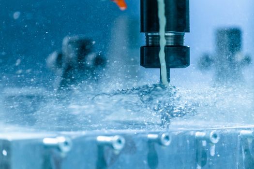 A close-up view on collet chuck and swarf wrapped over carbide drill while cnc drilling under liquid coolant. Feed and cutting speed adjusting problem. Milling machine debugging issue.