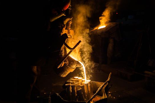 Industrial lost wax casting. The process of pouring for filling out ceramic shells with molten steel from ladle.