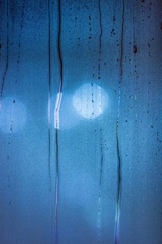 an abstract background of night wet window glass with smudges in blue tone gamma.