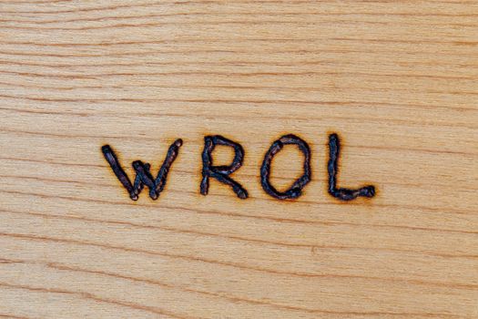 the abbreviation wrol - Without Rule Of Law - handwritten with woodburner on flat wooden surface in directly above flat lay perspective