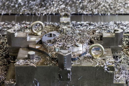a lot of swarf and iron chips after cnc milling on workpiece and 4-jaw chuck holder - close-up with selective focus and background blur