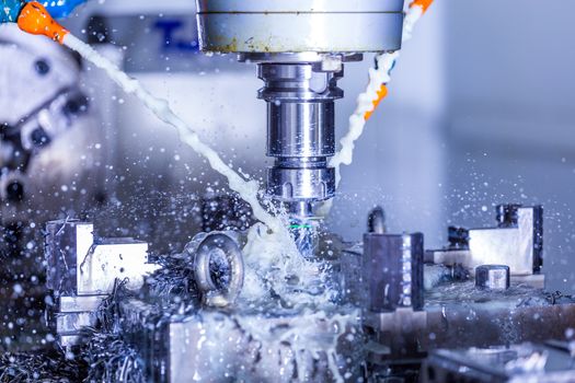 A process of vertical cnc steel milling with external water coolant streams, splashes and a lot of metal chips. Fast shutter speed for motion freezing.