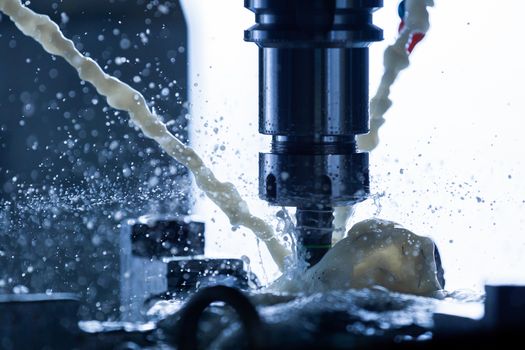 A process of vertical cnc steel milling with external water coolant streams, splashes and a lot of metal chips. Fast shutter speed for motion freezing. Shallow depth of field.