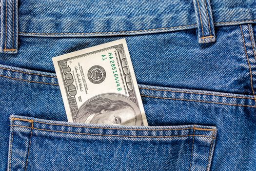 a hundred dollar banknote sticking out from rear jeans pocket - close-up.