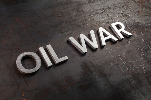 words oil war laid in line with silver metal letters on rusted heavy hot rolled uncoated steel sheet surface in diagonal perspective with selective focus