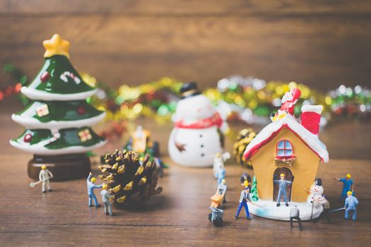 Creative concept with miniature people creating Christmas decorations on a wooden background. , Concept of teamwork.