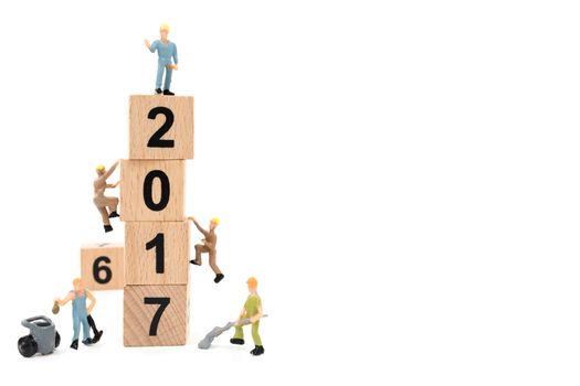 Miniature worker team building wooden block number 2017 on white background