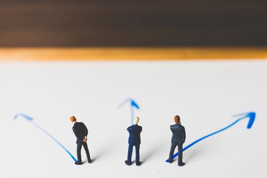 Miniature Businessman standing on arrow pathway , Business decision concept.