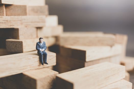 Miniature people : Business People sitting on wood block with wooden background