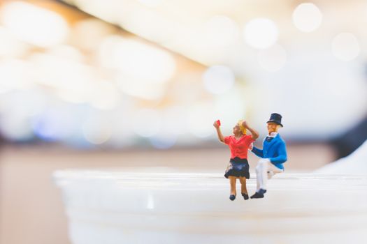 Miniature people : Couple sitting on cup , Valentine day's concept