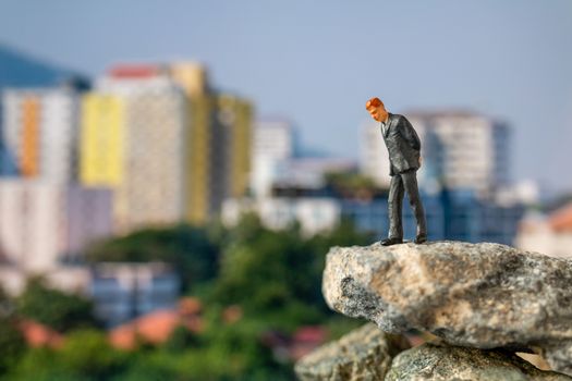 Miniature people , Businessman standing on The rock with building background