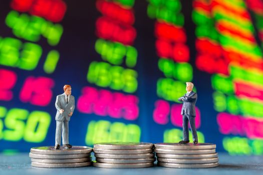 Miniature people , Businessman standing on stack of  Coins with graph display background