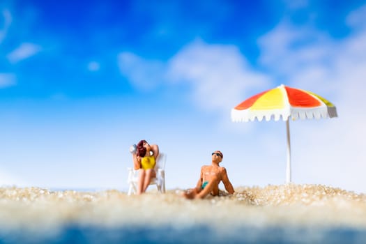 Miniature people sunbathing on The beach , Summer time concept