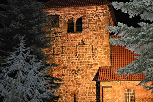 A church in the evening with fir trees in the foreground