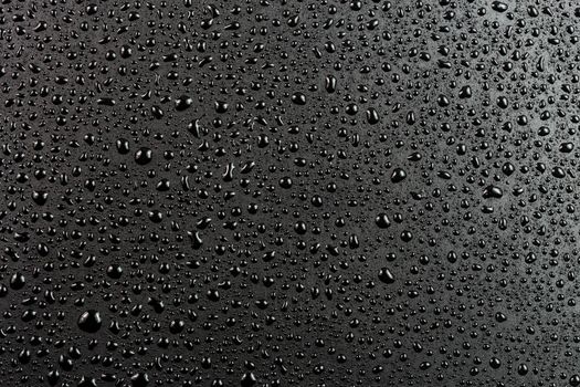 water drops on abstract flat black hydrophobic surface macro background.