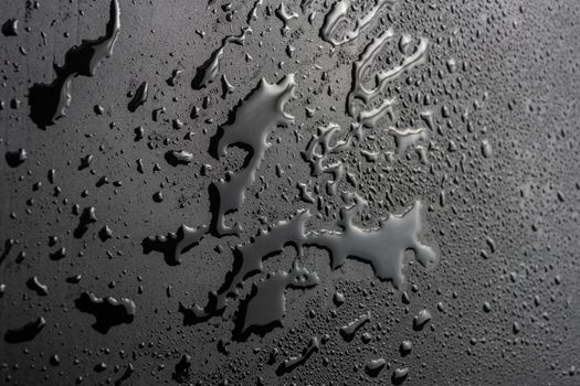 abstract background of wet black hydrophobic surface - close-up with selective focus and skewed perspective