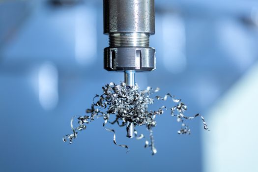 A close-up view on collet chuck and long swarf wrapped over carbide drill. Feed and cutting speed problem. Cnc milling machine debugging issue.