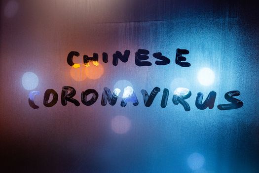 The words chinese coronavirus handwritten on sweat window glass surface at night. Pandemic concept.