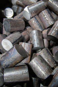 a pile of raw steel short bars cutted by saw - workpieces prepaired for forging, close-up with selective focus and background blur