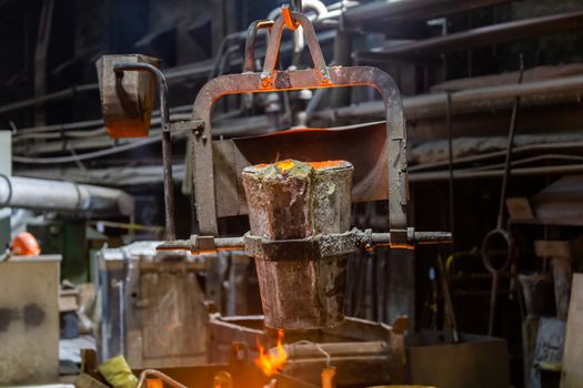 small metallurgical ladle with molten steel moves on a hook of crane - close-up view