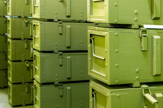 stacks of abstract green military crates without any markings - close-up with selective focus and background blur.