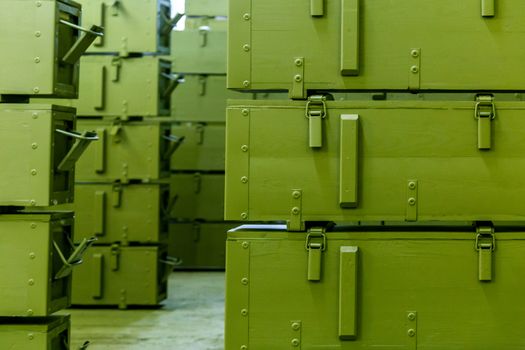 stacks of abstract green military crates without any markings - close-up with selective focus and background blur.