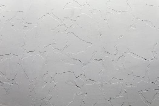 Abstract white unostentatious background and texture. A plaster wall with old cracked layer under new one. Top-down light direction.