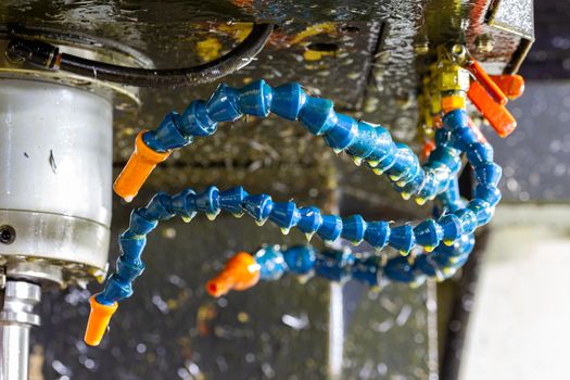 blue plastic water and air flexible hoses of milling machine covered by oil and steel chips.