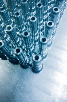 Shiny blue steel parts background, long clean steel threaded rods after fine cnc turning.