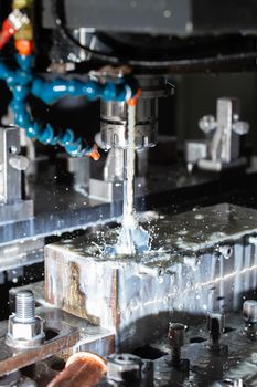 a process of cnc vertical reaming with liquid coolant flow, close-up with selective focus