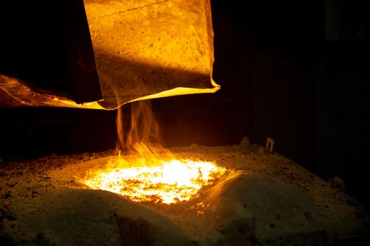 metallurgical furnace with exhaust hood and melting metal with slag and vapor, close-up with selective focus