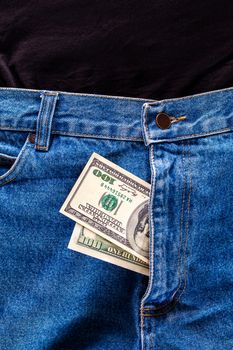 a two hundred dollar bills inside codpiece of blue jeans close-up with selective focus.