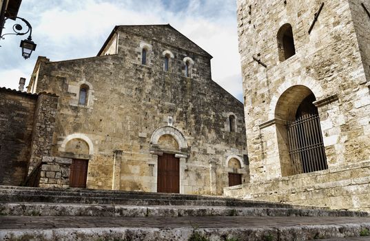 ANAGNI-ITALY-July 2020- facade of the cathedral and bell tower against blue sky ,simple facade with three ports with scraps of old Roman marble and beautiful  staircase