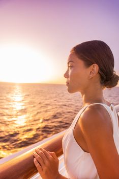 Cruise luxury travel woman europe destination vacation holiday. Girl enjoying sunset view in elegant white evening dress from balcony suite deck. Asian beauty relaxing.