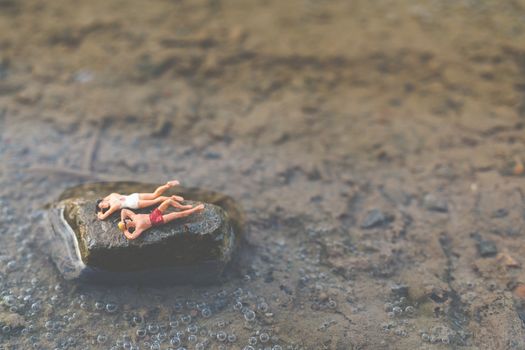 Miniature people wearing swimsuit relaxing on the beach , Summer concept