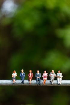 Miniature people : business people sitting on a  wire with green background 
, Business  team concepts