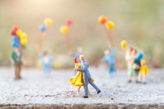 Miniature people : Couple dancing  with people holding  balloons background