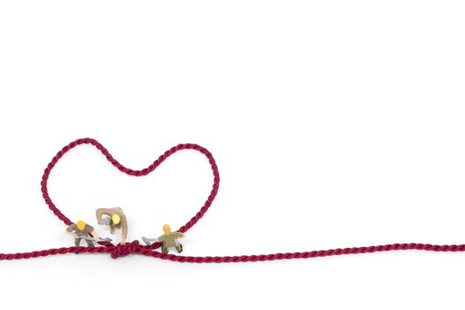 Miniature worker team building Heart Shaped with rope on white background