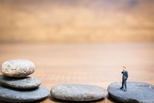Miniature people : Businessman standing on stone , Challenges and risks Concept