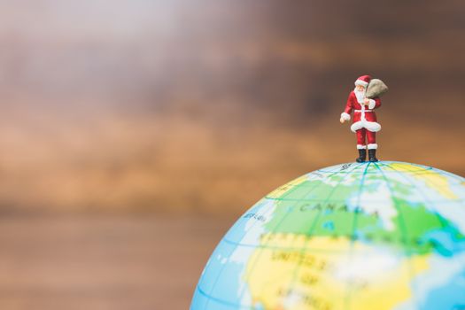 Miniature people : Santa Claus carrying on The globe